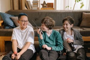 Three middle school aged boys sitting on the floor. Middle boy has a walkie talkie and all are smiling.