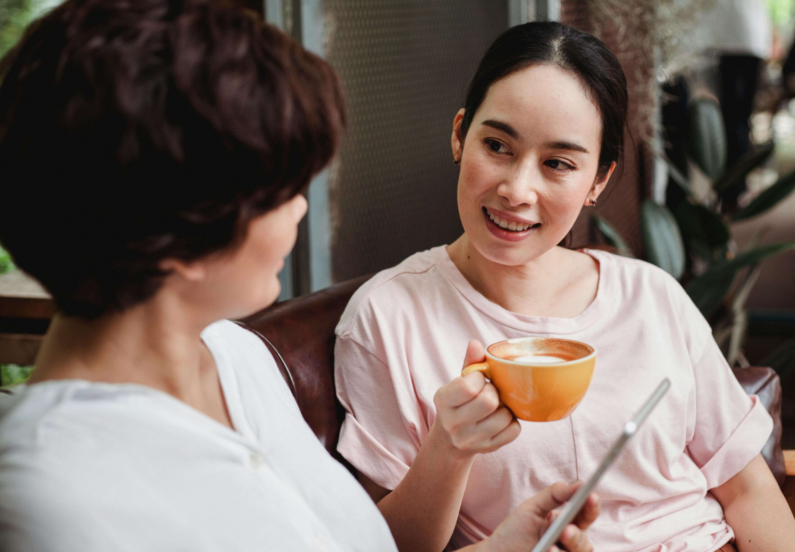 woman holding coffee cup smiling at her friend