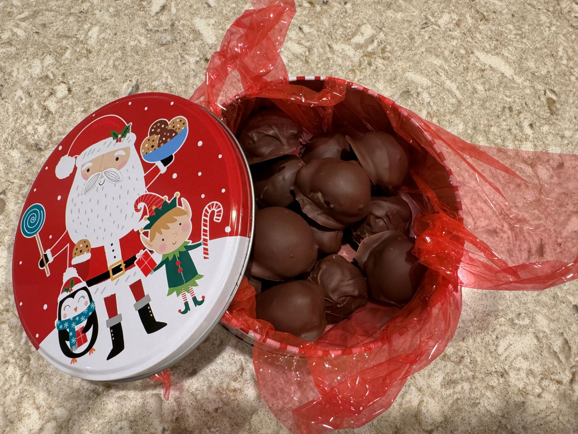 chocolate covered truffles in a Christmas tin with Santa on the cover