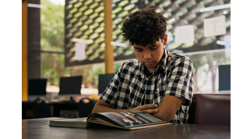 Teen boy reading book alone